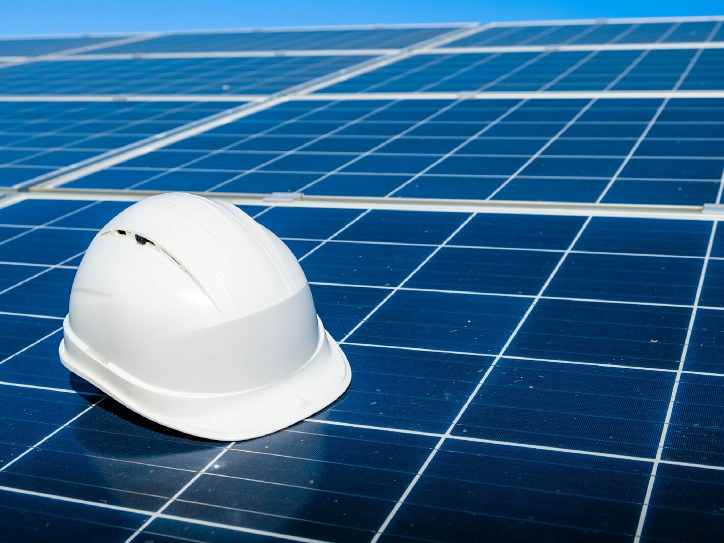 a white hard hat sitting on top of a solar panel